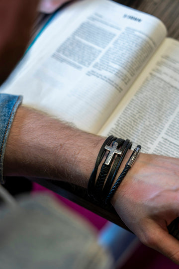a man is holding a book with a cross on it