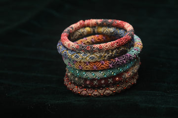 Stack of colorful beaded bracelets on dark fabric