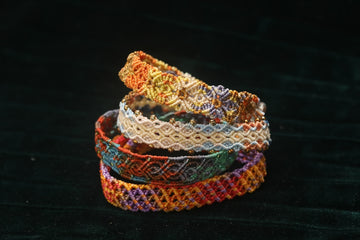 Stack of colorful woven bracelets on dark background